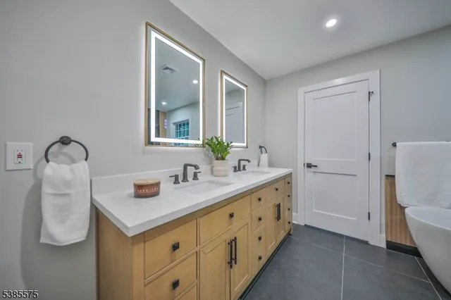 a bathroom with double vanity sink a mirror and a toilet