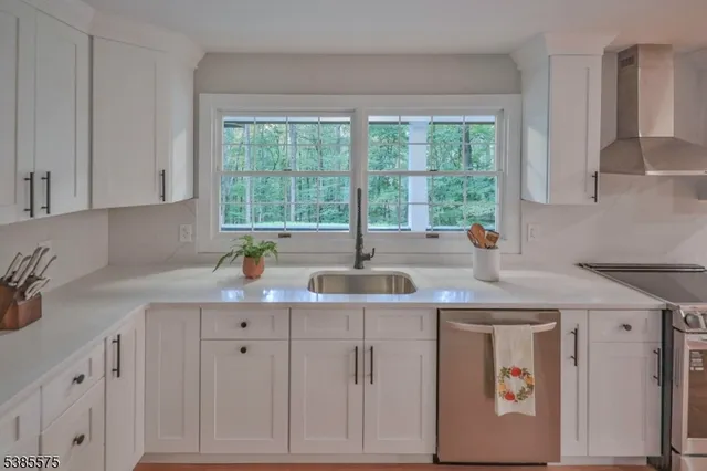 a kitchen with white cabinets and a window
