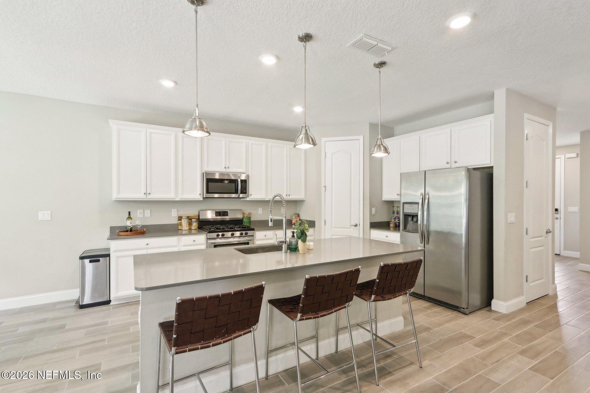 367 Sweet Oak Way St. Augustine, FL 32095 - Photo 14 of 51 a kitchen with stainless steel appliances kitchen island granite countertop a refrigerator a stove a sink a dining table and chairs with wooden floor