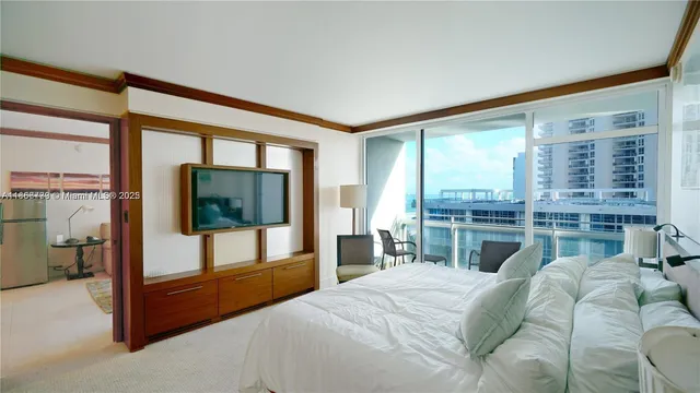 a bedroom with a bed and a flat tv screen next to a large window