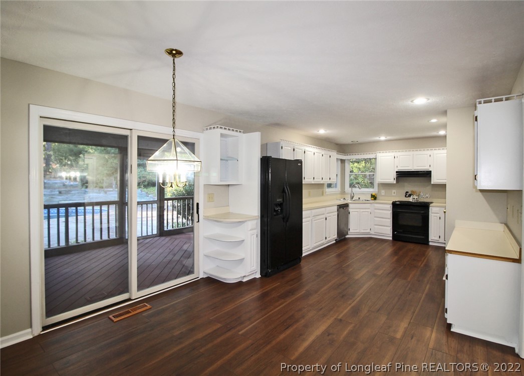 297 Fieldcrest Road Southern Pines, NC 28387 - Photo 11 of 32 a kitchen with stainless steel appliances kitchen island granite countertop a refrigerator a sink a stove and white cabinets with wooden floor