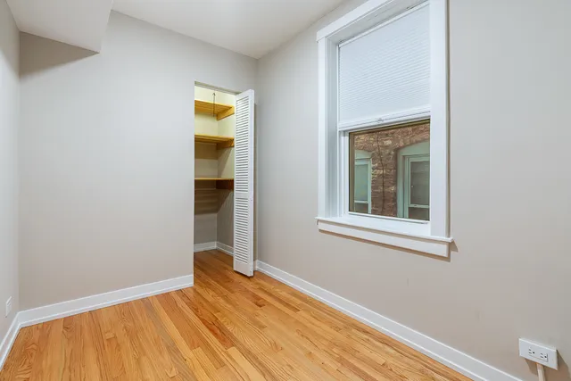 a view of a bedroom with wooden floor and a window