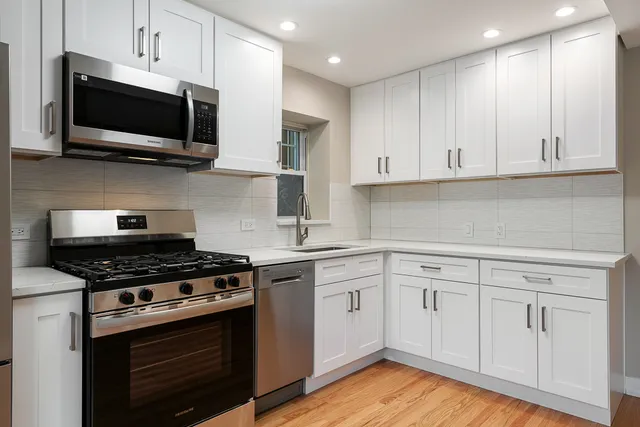 a kitchen with cabinets stainless steel appliances and wooden floor