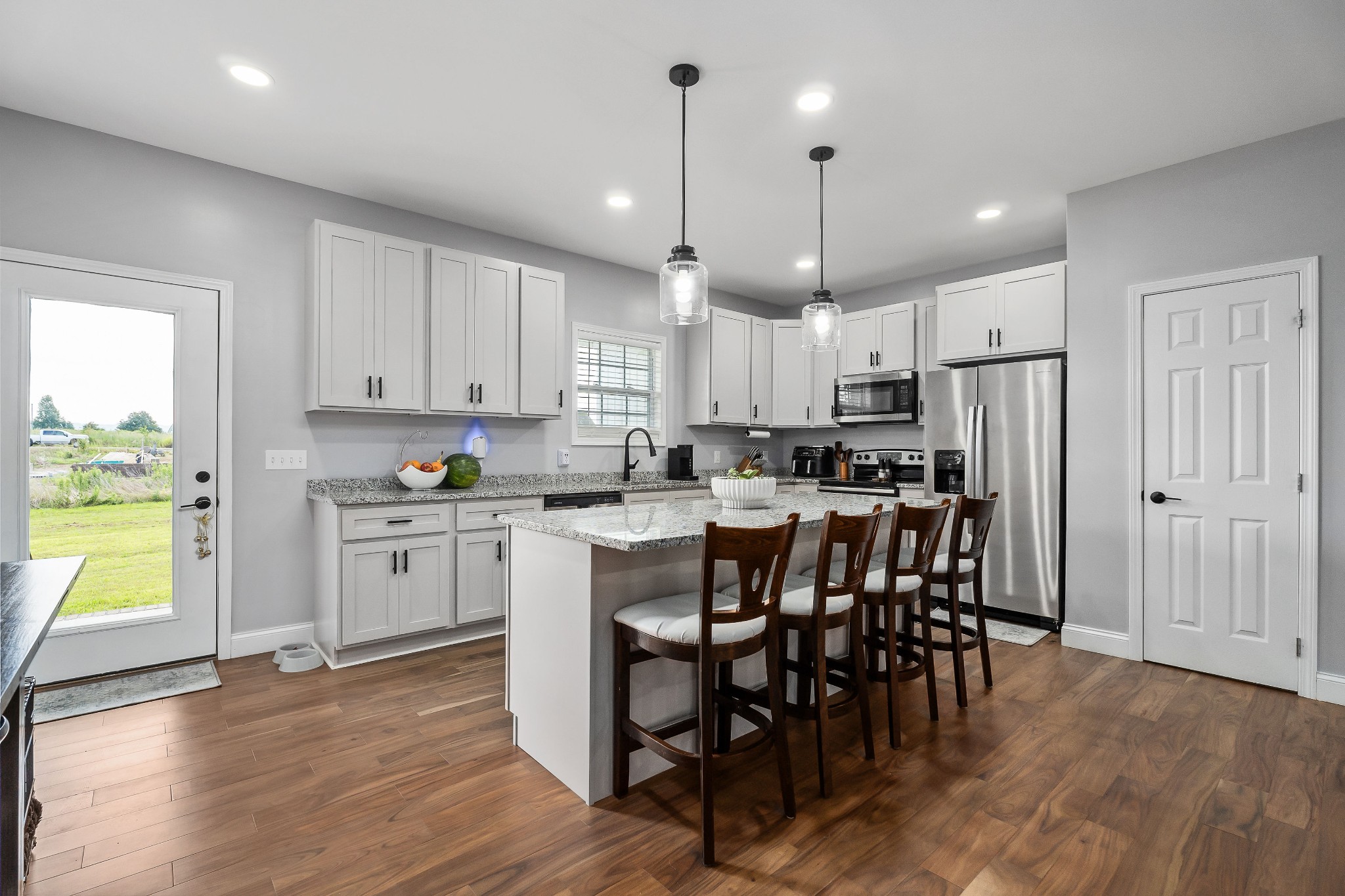 1042 North Spring Street Sparta, TN 38583 - Photo 16 of 36 a kitchen with stainless steel appliances granite countertop a stove a refrigerator a kitchen island a dining table and chairs with wooden floor