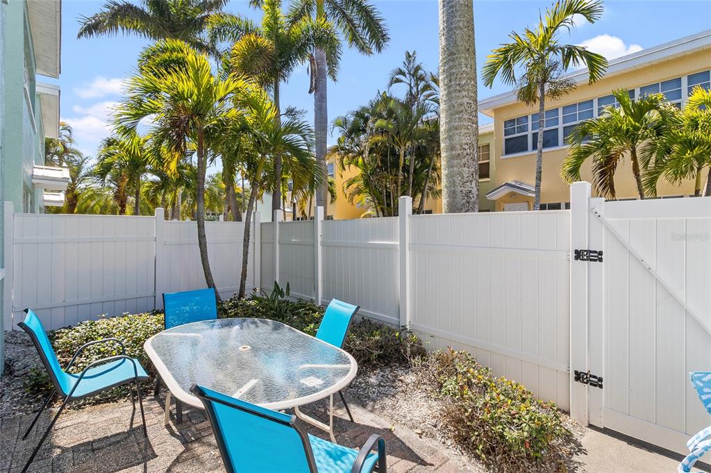 19417 Gulf Boulevard, Unit C109 Indian Rocks Beach, FL 33785 - Photo 7 of 48 a backyard of a house with table and chairs plants
