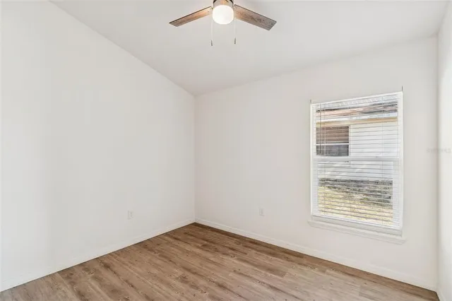 an empty room with a window and a ceiling fan