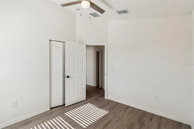 an empty room with wooden floor cabinet and hallway