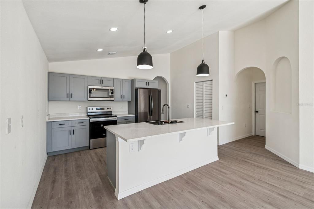 119 Winchester Lane Haines City, FL 33844 - Photo 6 of 24 a large kitchen with stainless steel appliances kitchen island granite countertop a stove a sink a refrigerator and a wooden floor