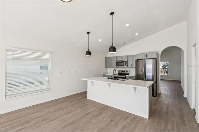 a kitchen with stainless steel appliances granite countertop a sink a stove and a wooden floors