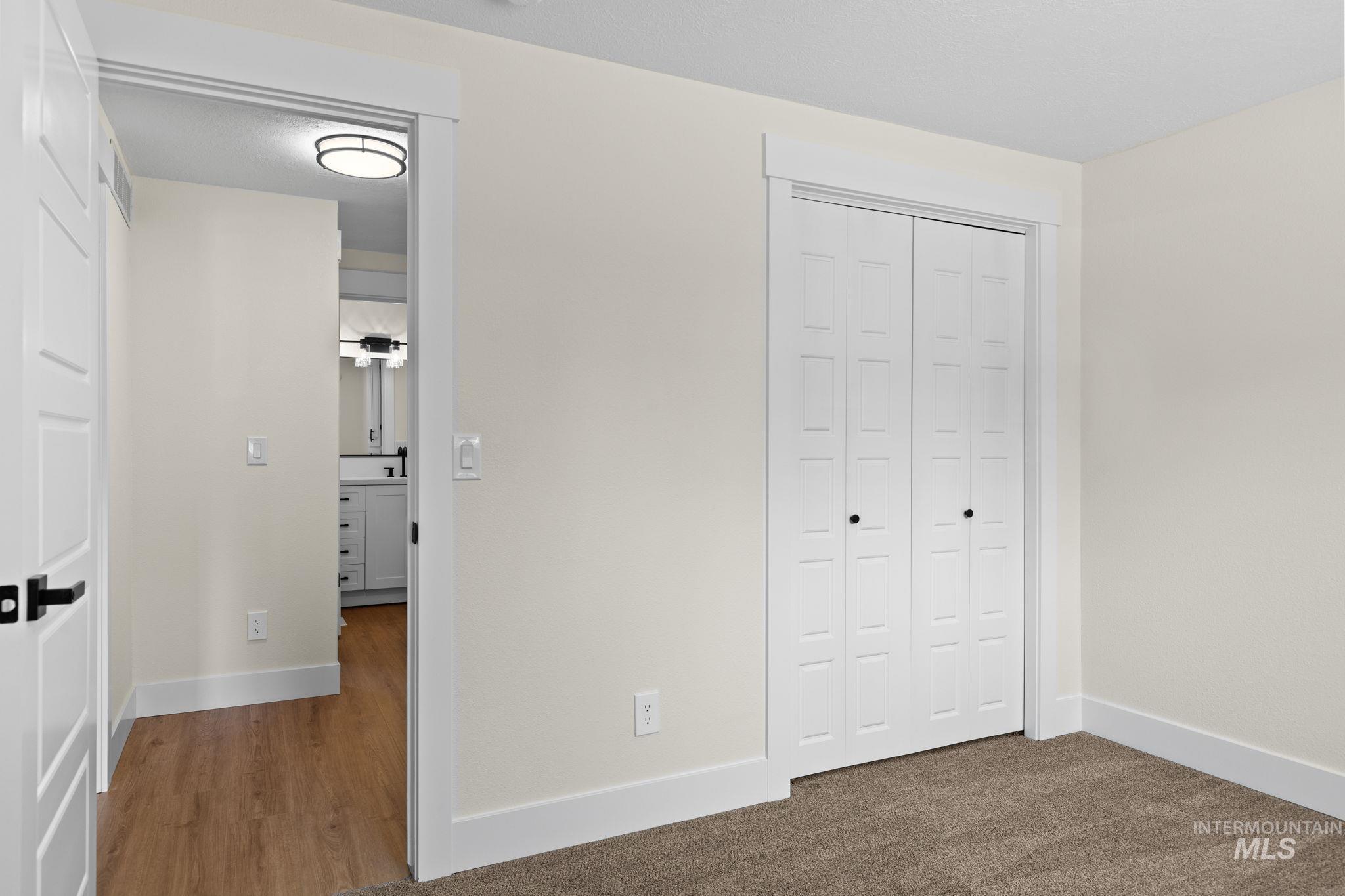 1675 Country Terrace Way Meridian, ID 83642 - Photo 24 of 50 Carpeted flooring, white bi-fold closet doors, and a wood-finish flooring visible through the doorway