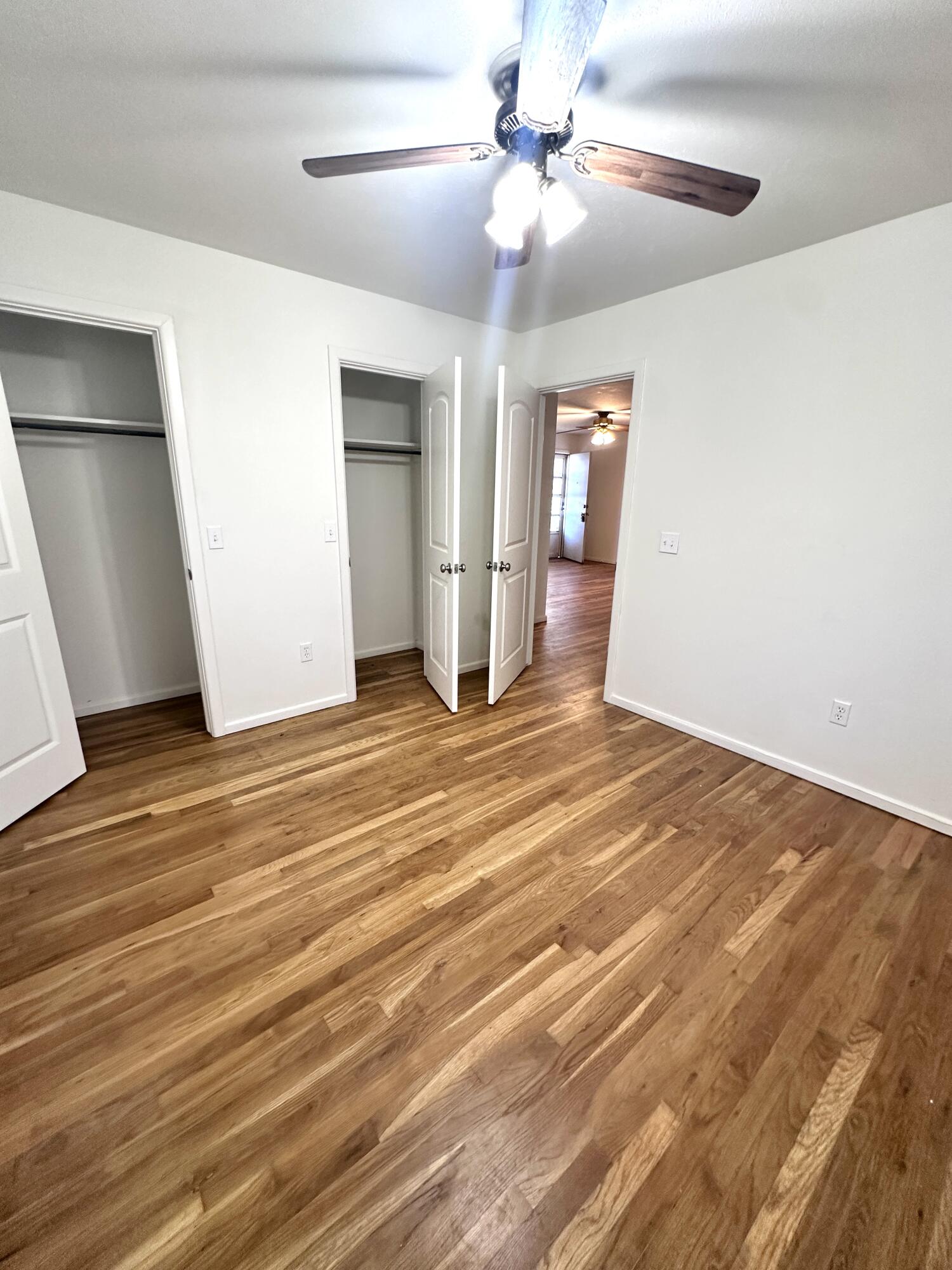 3719 30th Street, Unit A Lubbock, TX 79410 - Photo 11 of 16 a view of an empty room with wooden floor and a ceiling fan