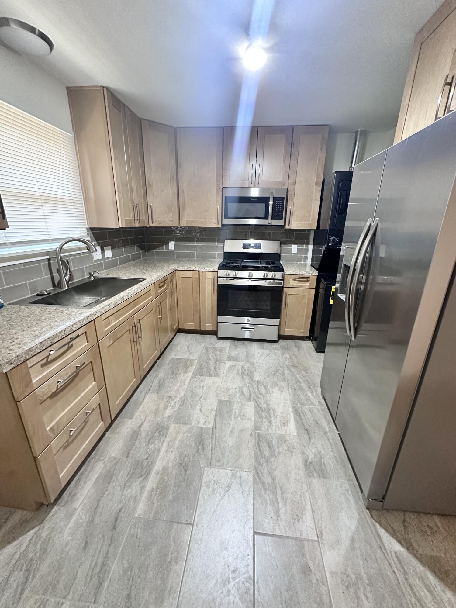 3719 30th Street, Unit A Lubbock, TX 79410 - Photo 4 of 16 a kitchen with stainless steel appliances granite countertop a stove a sink and a refrigerator