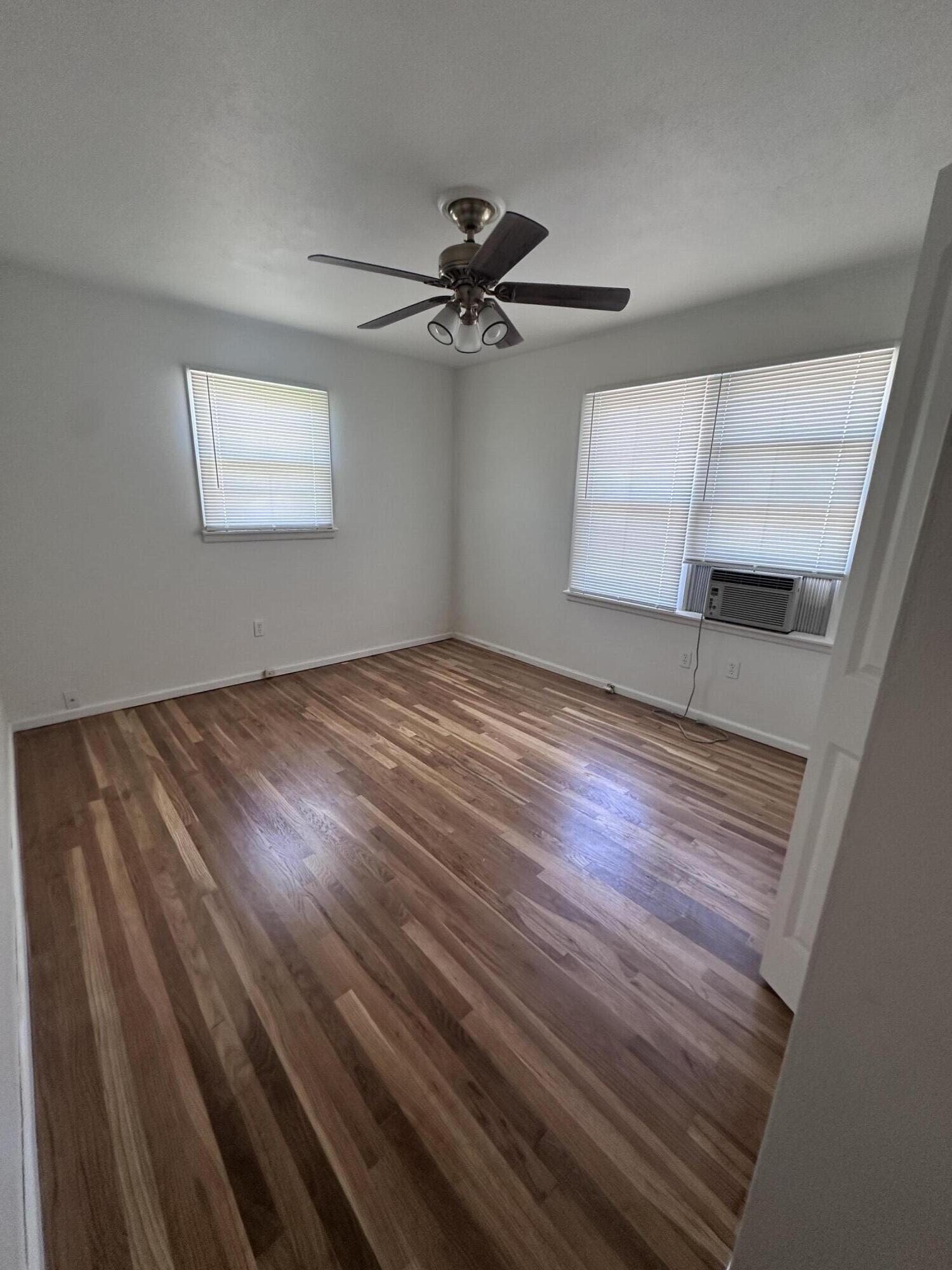 3719 30th Street, Unit A Lubbock, TX 79410 - Photo 7 of 16 an empty room with wooden floor fan and windows