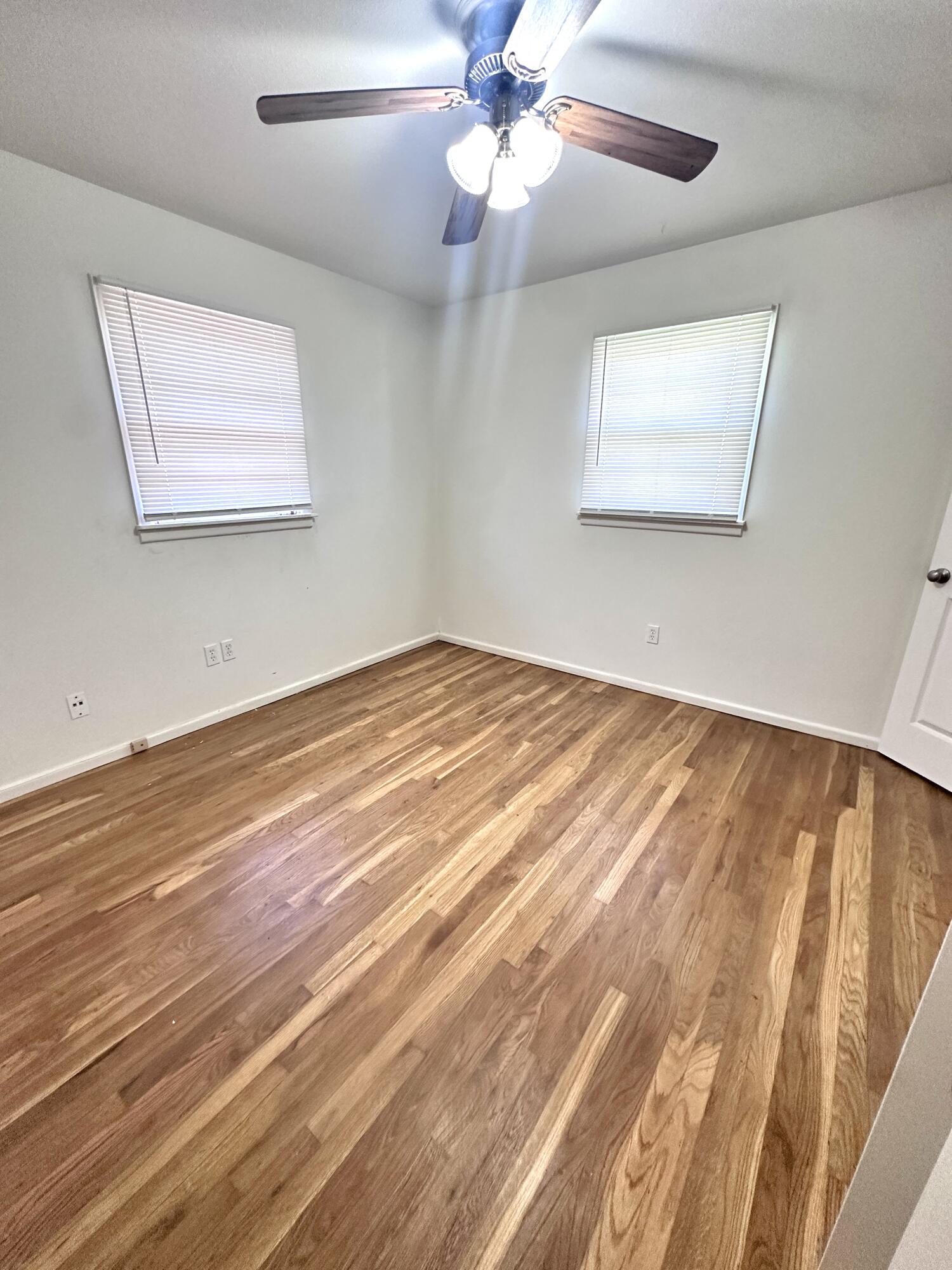3719 30th Street, Unit A Lubbock, TX 79410 - Photo 10 of 16 a view of an empty room with wooden floor and a ceiling fan