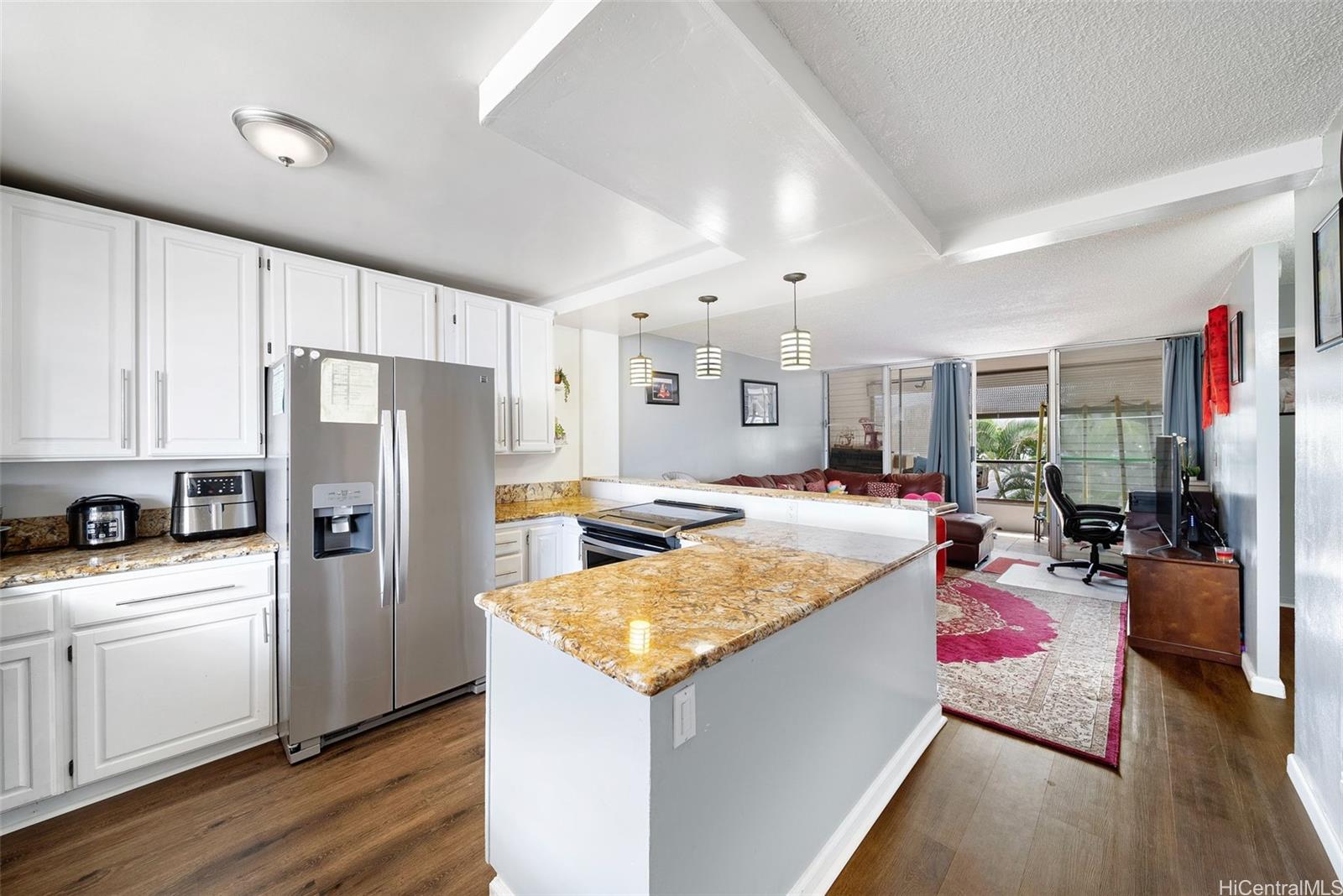 a large kitchen with a stove a refrigerator a sink dishwasher and white cabinets with wooden floor