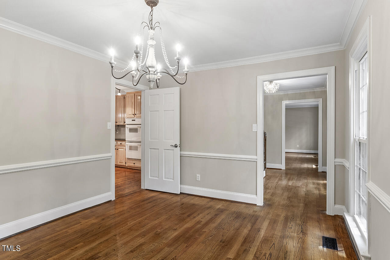 5200 Smallwood Court Raleigh, NC 27613 - Photo 14 of 38 an empty room with wooden floor chandelier and windows