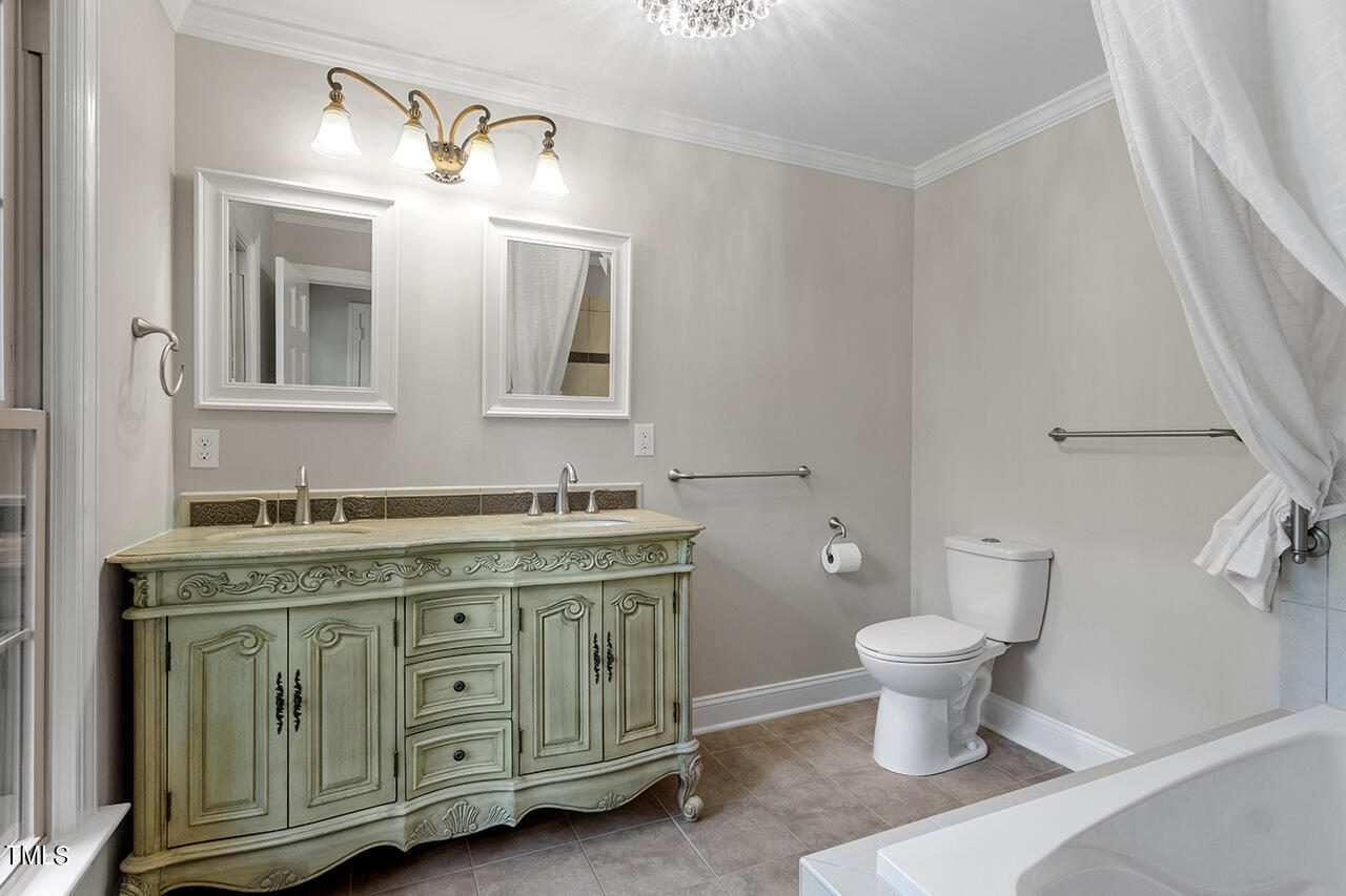 5200 Smallwood Court Raleigh, NC 27613 - Photo 18 of 38 a spacious bathroom with a double vanity sink a toilet and a mirror