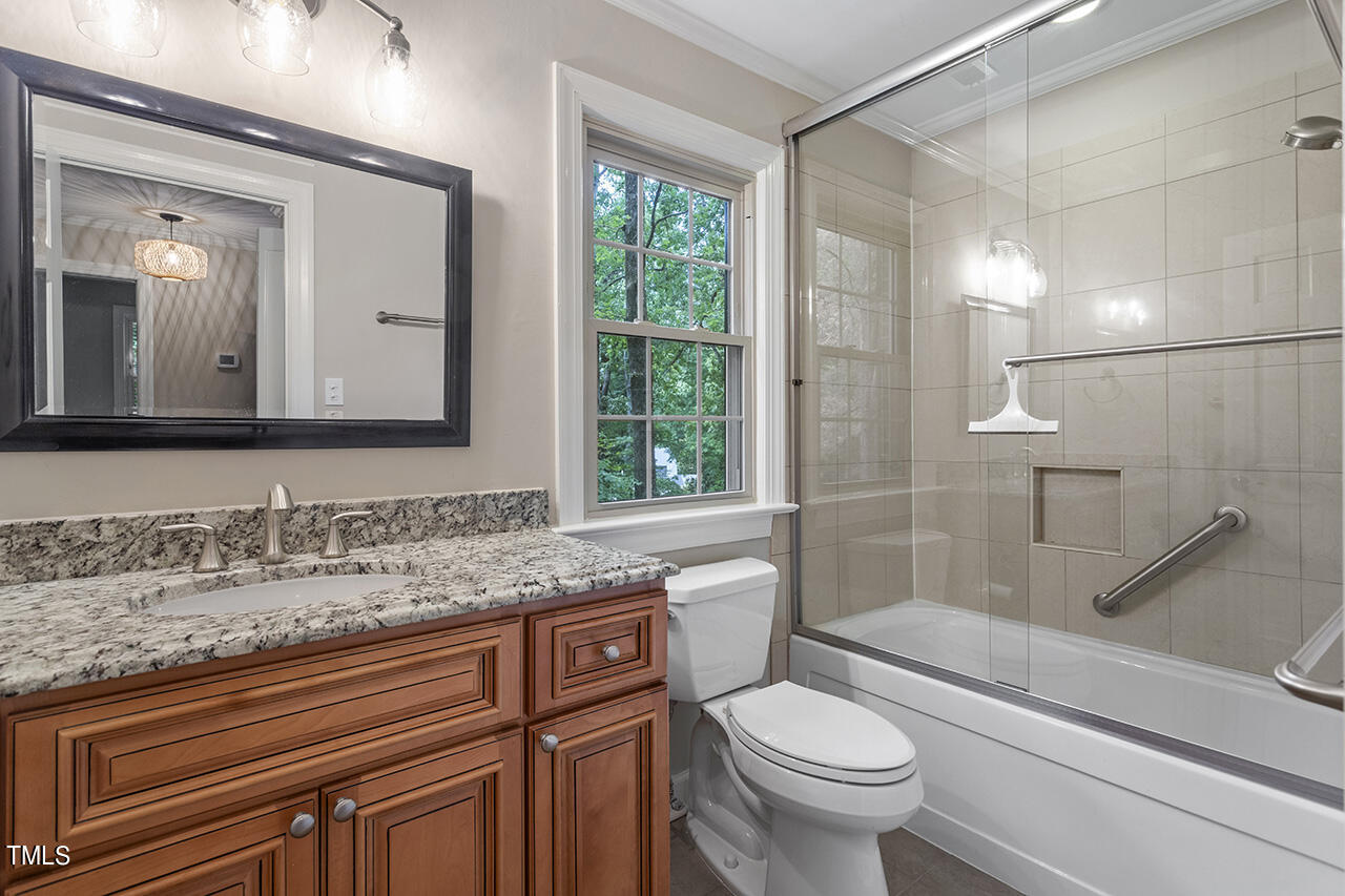 5200 Smallwood Court Raleigh, NC 27613 - Photo 26 of 38 a bathroom with a granite countertop toilet a sink and a mirror