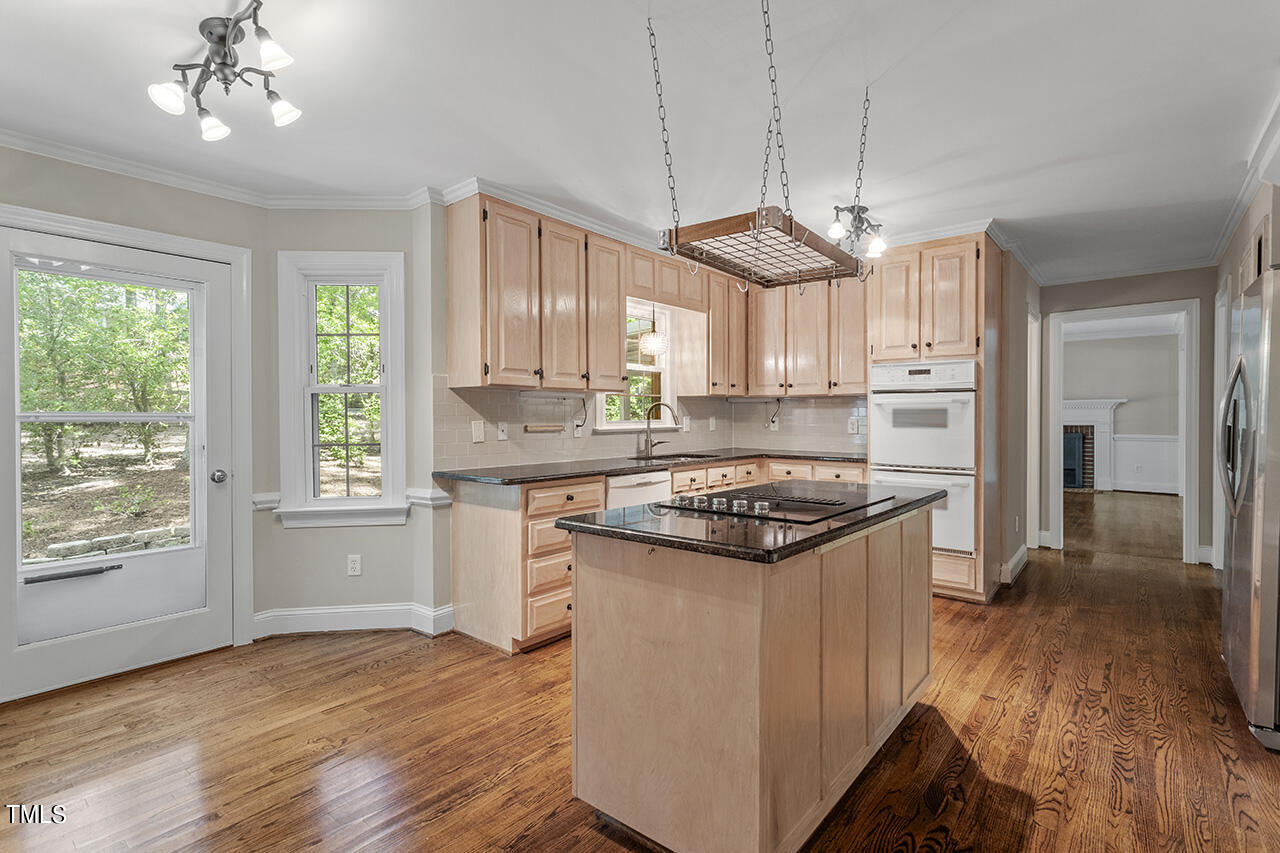 5200 Smallwood Court Raleigh, NC 27613 - Photo 9 of 38 a kitchen with a stove a sink a window and wooden floor