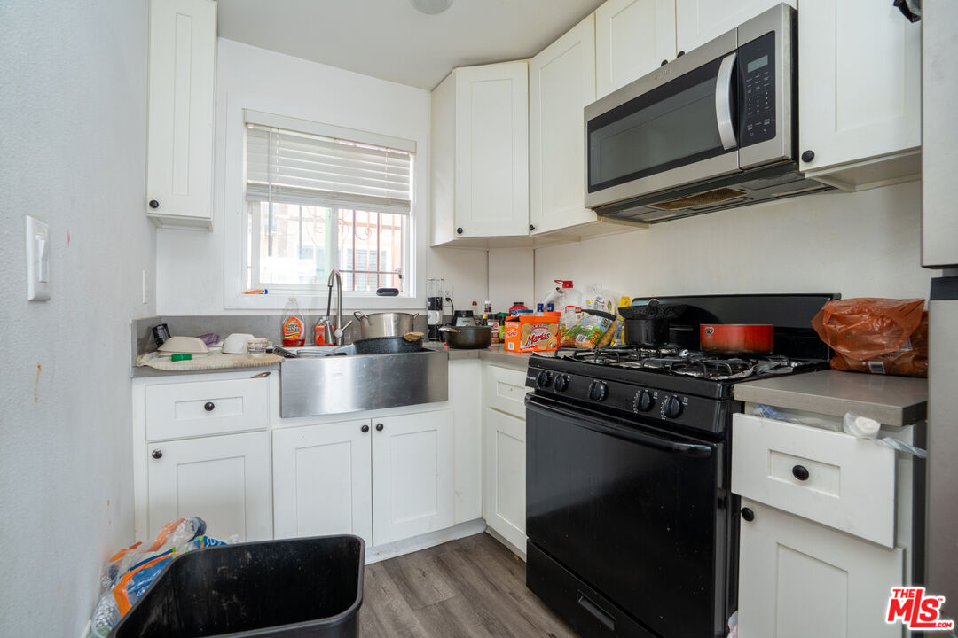1047 East 33rd Street Los Angeles, CA 90011 - Photo 11 of 24 a kitchen with stainless steel appliances granite countertop white cabinets a stove a sink and a microwave