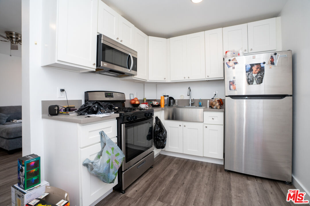 1047 East 33rd Street Los Angeles, CA 90011 - Photo 18 of 24 a kitchen with a refrigerator a microwave a sink and cabinets