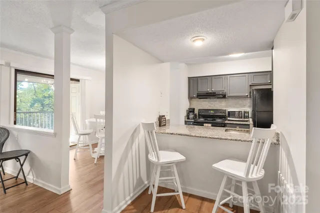 a kitchen with stainless steel appliances a dining table chairs refrigerator and microwave