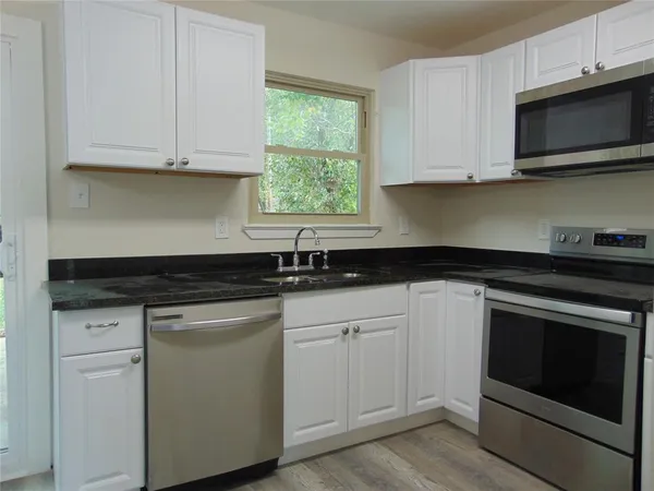 a kitchen with white cabinets and a stove with wooden floor