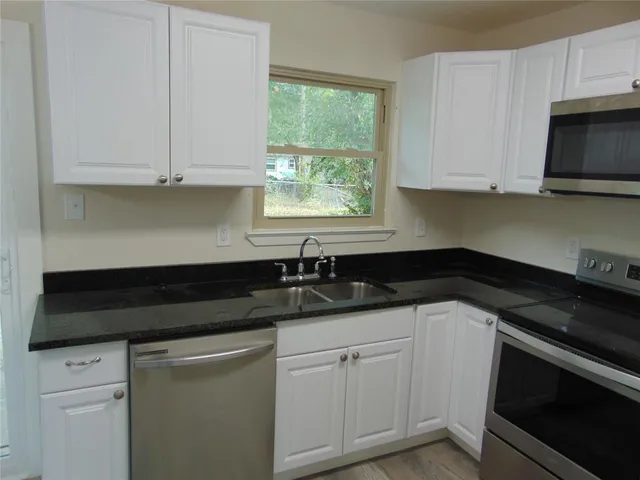 a kitchen with granite countertop white cabinets and a stove