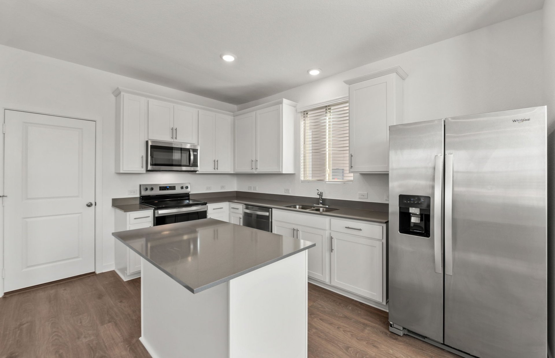 590 Rubber Tree Way Buda, TX 78610 - Photo 2 of 22 a kitchen with stainless steel appliances granite countertop a refrigerator a sink a stove a microwave and white cabinets