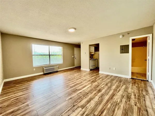 an empty room with wooden floor and window