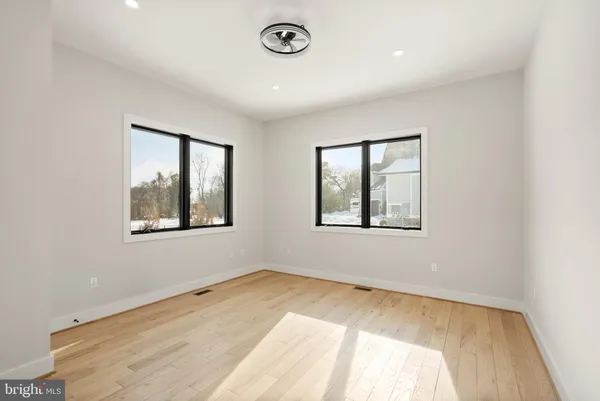 a view of an empty room with wooden floor and closet