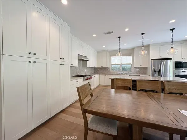 a kitchen with stainless steel appliances granite countertop a table chairs sink refrigerator and cabinets