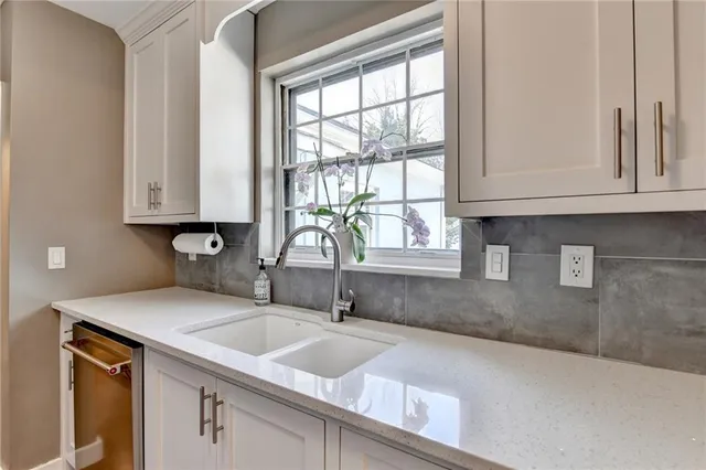a kitchen with granite countertop a sink window and cabinets