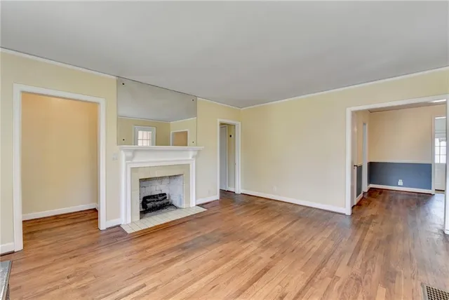 an empty room with wooden floor fireplace and windows