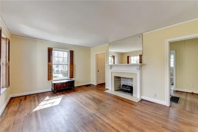 an empty room with fireplace wooden floor and windows