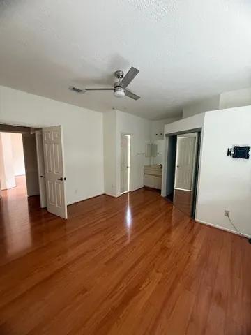 a view of empty room with wooden floor and ceiling fan