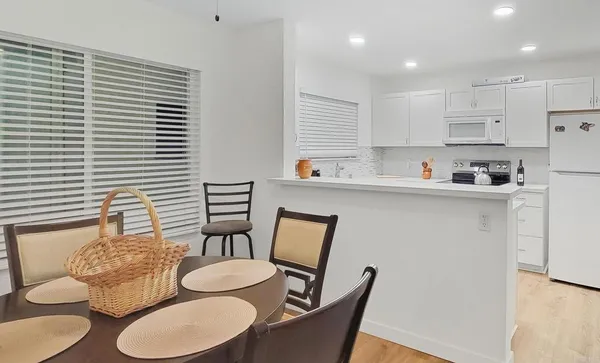 a kitchen with stainless steel appliances granite countertop a dining table chairs and a window