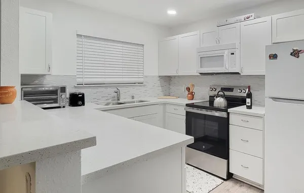 a kitchen with stainless steel appliances white cabinets a sink a stove a refrigerator and cabinets