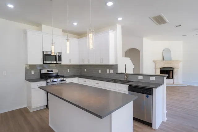 a kitchen with a sink and a stove top oven with wooden floor