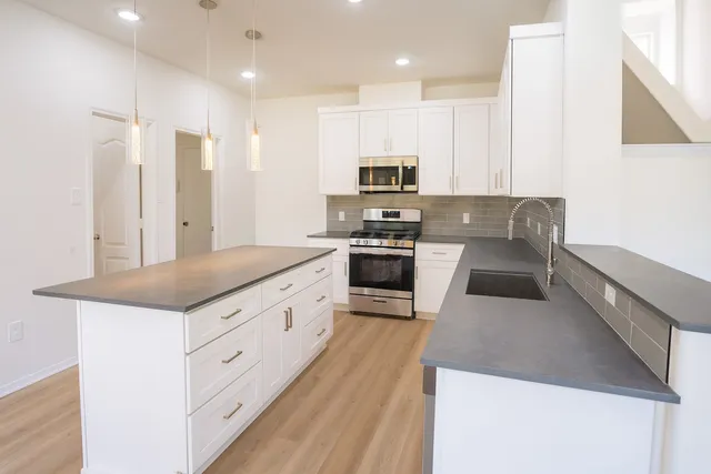 a kitchen with granite countertop a sink a counter top space stainless steel appliances and cabinets