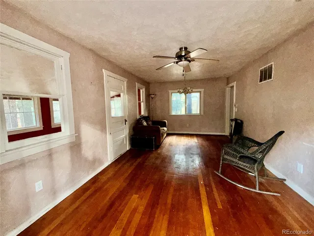 a view of a livingroom with furniture a ceiling fan and wooden floor