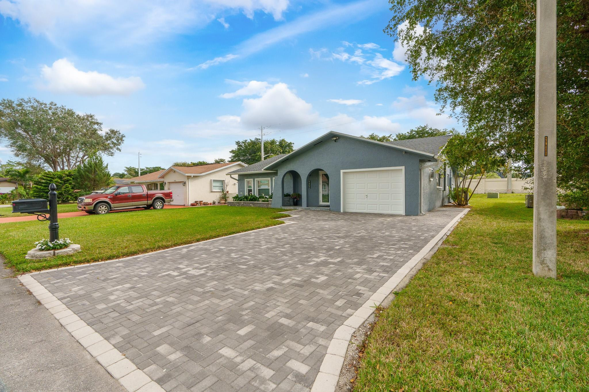 9402 Northwest 70th Street Tamarac, FL 33321 - Photo 4 of 60 a white house with a small yard and large trees