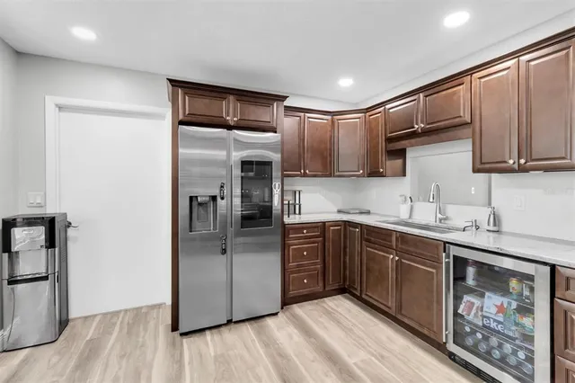 a kitchen with stainless steel appliances granite countertop a refrigerator a sink dishwasher a stove with wooden cabinets and floor