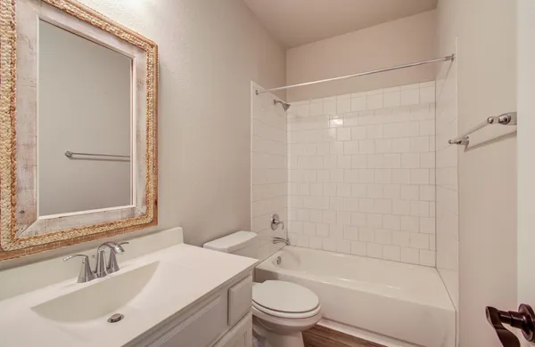 a bathroom with a bathtub shower sink vanity mirror and toilet
