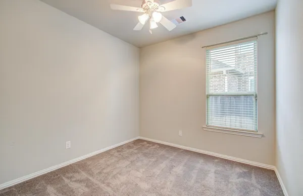 an empty room with a window and a fan