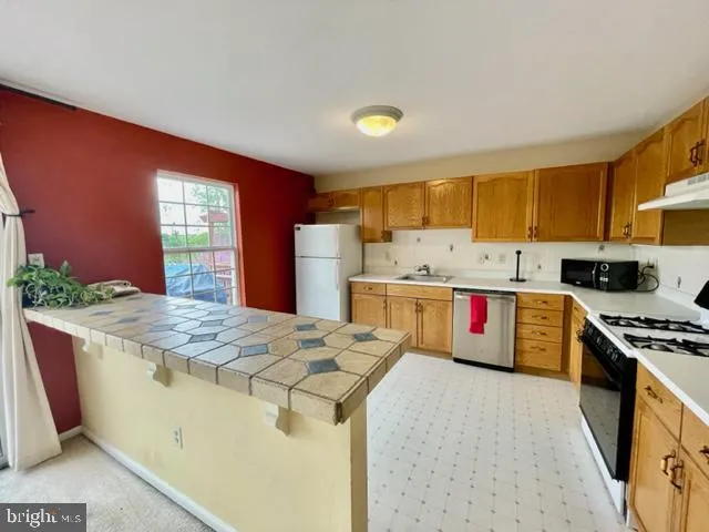 a kitchen with stainless steel appliances kitchen island granite countertop a refrigerator and a stove top oven