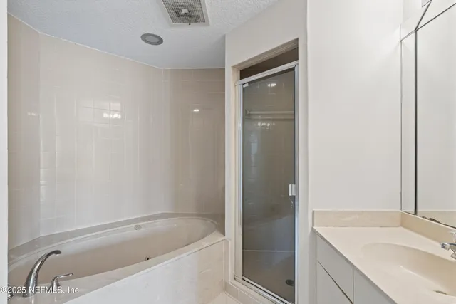 a bathroom with a tub sink vanity and granite