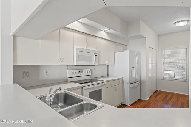 a kitchen that has a sink cabinets counter space and appliances