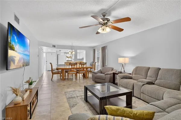 a living room with furniture kitchen view and a flat screen tv