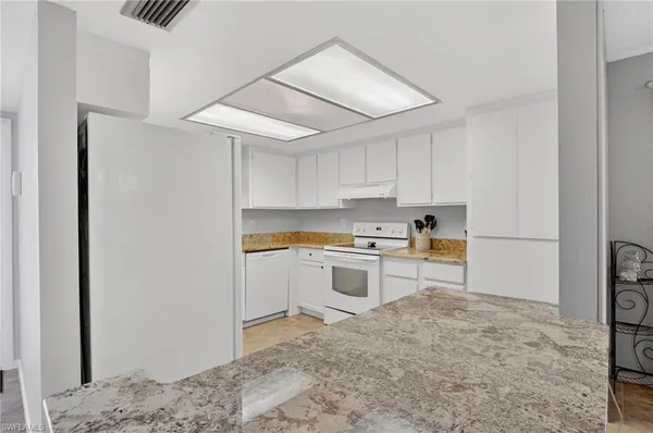 a kitchen with a refrigerator and white cabinets